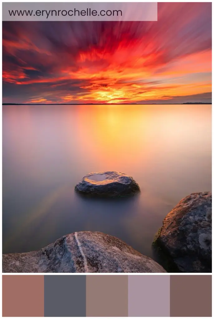 Gray rock formation on a body of water during sunset, showcasing warm and cool tones in a tranquil natural setting.