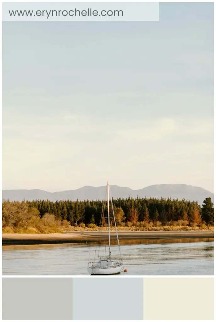 White sailboat on a body of water during the daytime, showcasing soft gray, blue-gray, and beige tones in a tranquil setting.