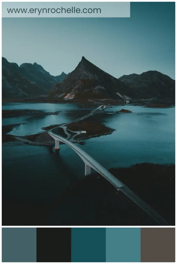 A white bridge spanning across a lake with a mountainous backdrop during daytime, showcasing deep teal waters, lush green vegetation, and the serene harmony of nature and architecture.