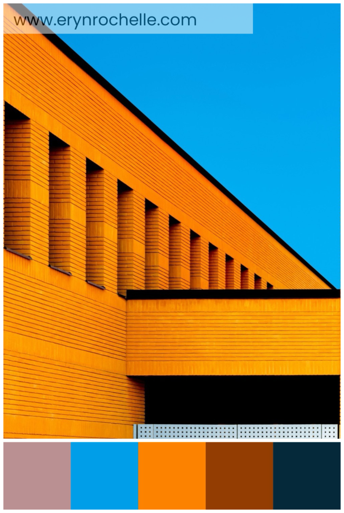 A brown concrete building set against a bright blue sky during daytime, featuring a color palette of warm taupe, sky blue, vivid orange, rust red, and deep navy tones.